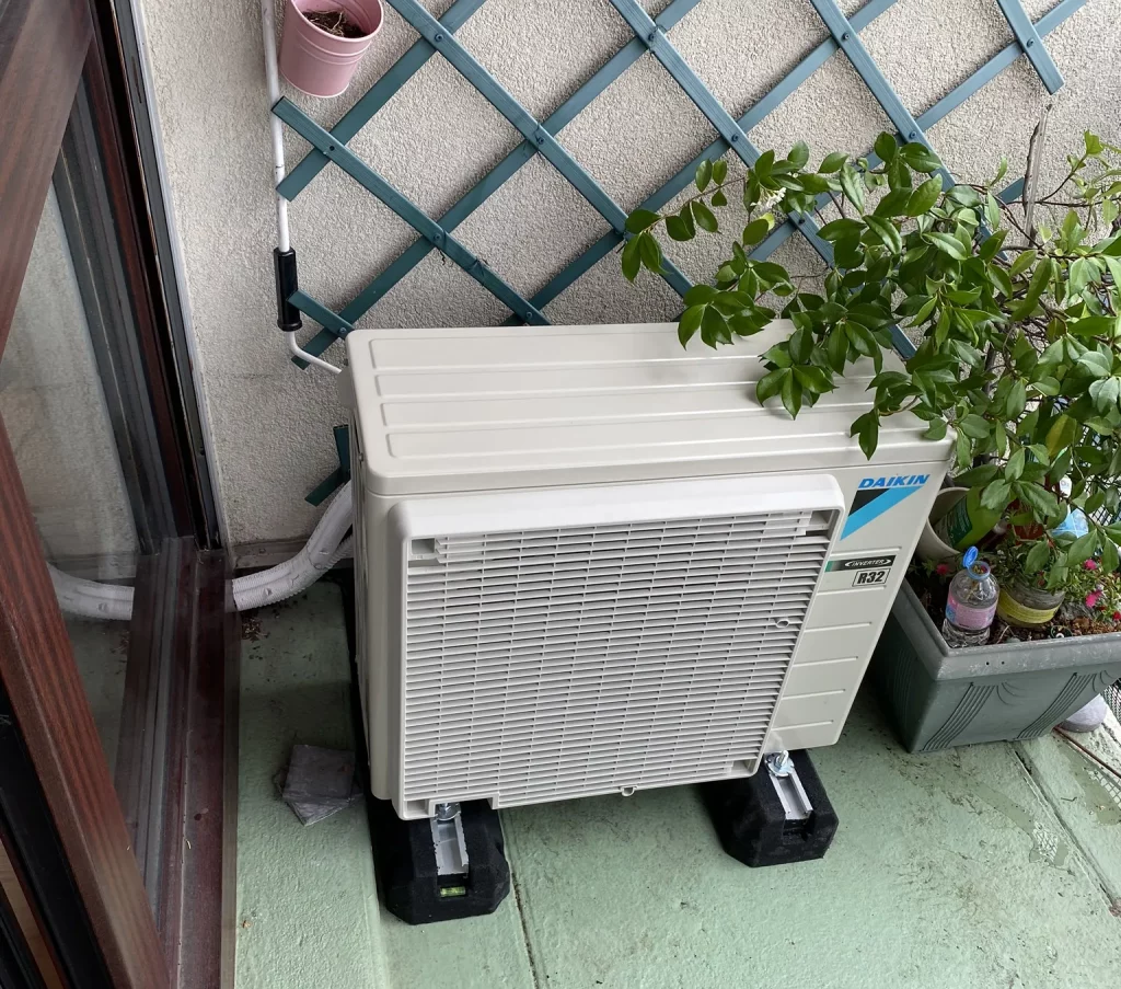 Climatisation Daikin réversible groupe extérieur blanche a côté d'une baie vitré