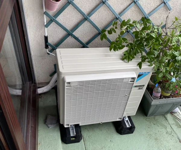 Climatisation Daikin réversible groupe extérieur blanche a côté d'une baie vitré